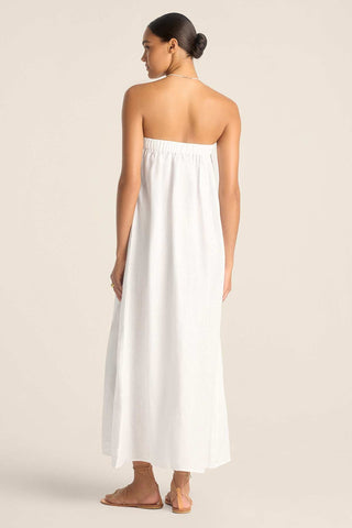 Woman turned away wearing a white bandeau style full length beach dress