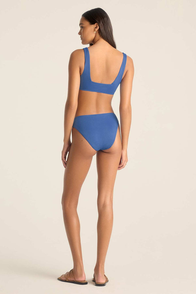 Woman faced away wearing a blue swim top with matching swim bottoms