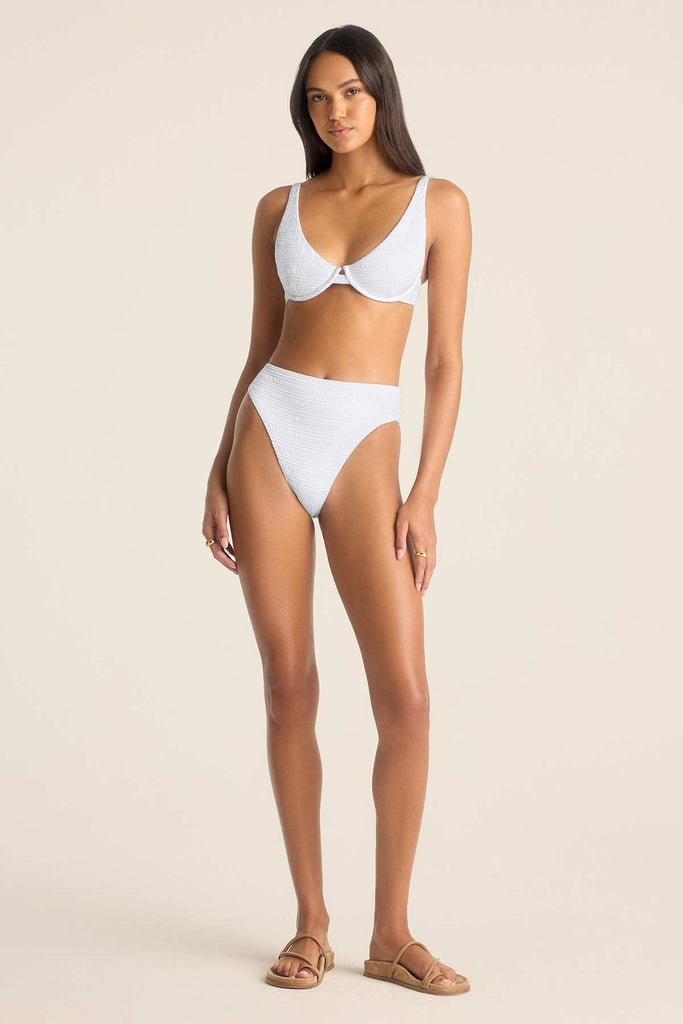 Woman wearing a white bikini top and matching high waisted white swim bottoms