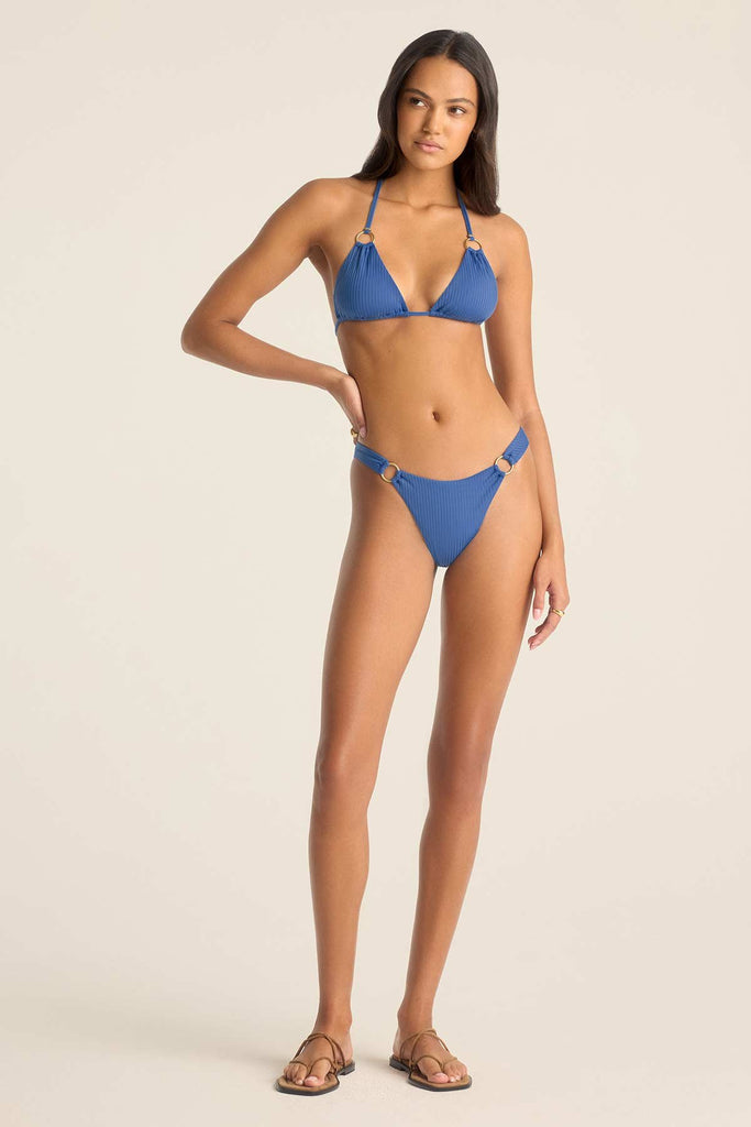 Woman wearing a blue bikini top with O ring details with matching swim bottoms
