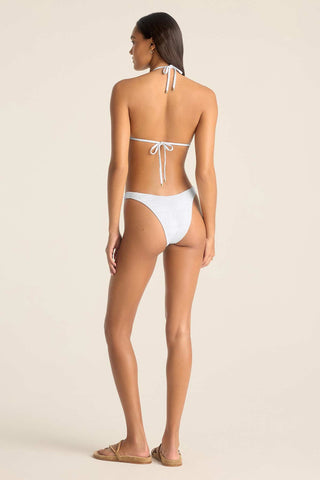 Woman turned away wearing a white string bikini top with matching swim bottoms