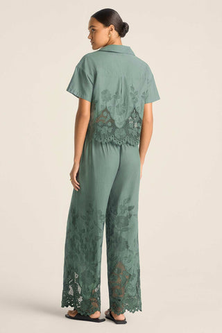 Woman faced away wearing a sea green lacy short sleeve beach shirt with matching pants 