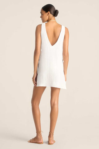 Woman turned away wearing a white tank top style beach dress